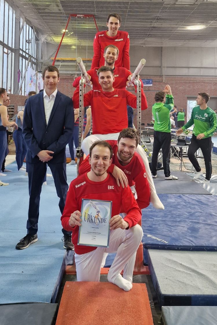 Das Turnteam Elbfelge posiert für ein Gruppenbild beim Liga-Auftakt in Thüringen. Die Turner stehen vor dem Barren.